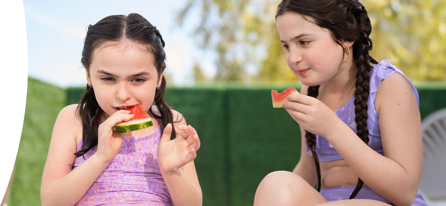 Clare, living with Rett syndrome, eating watermelon with her sister