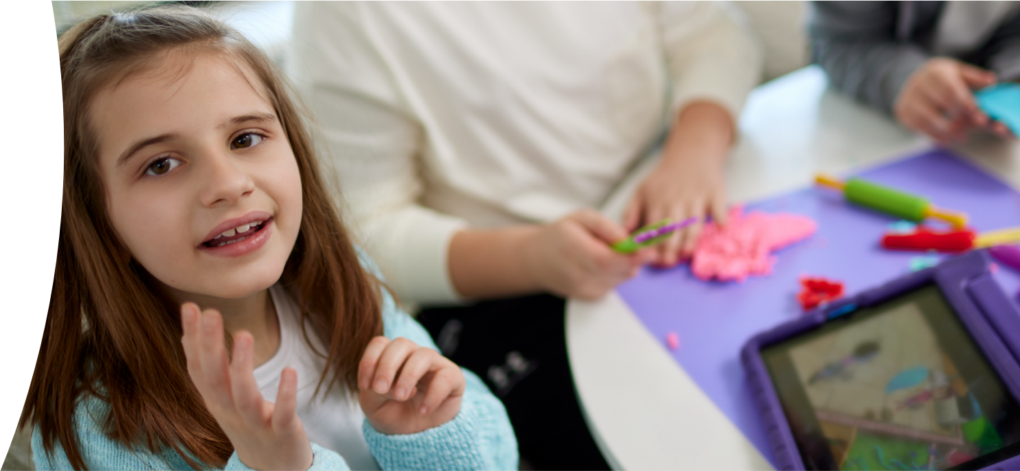 Kate, age 9, living with Rett syndrome and on DAYBUE® since 2021, playing with a tablet and doing crafts with her mom